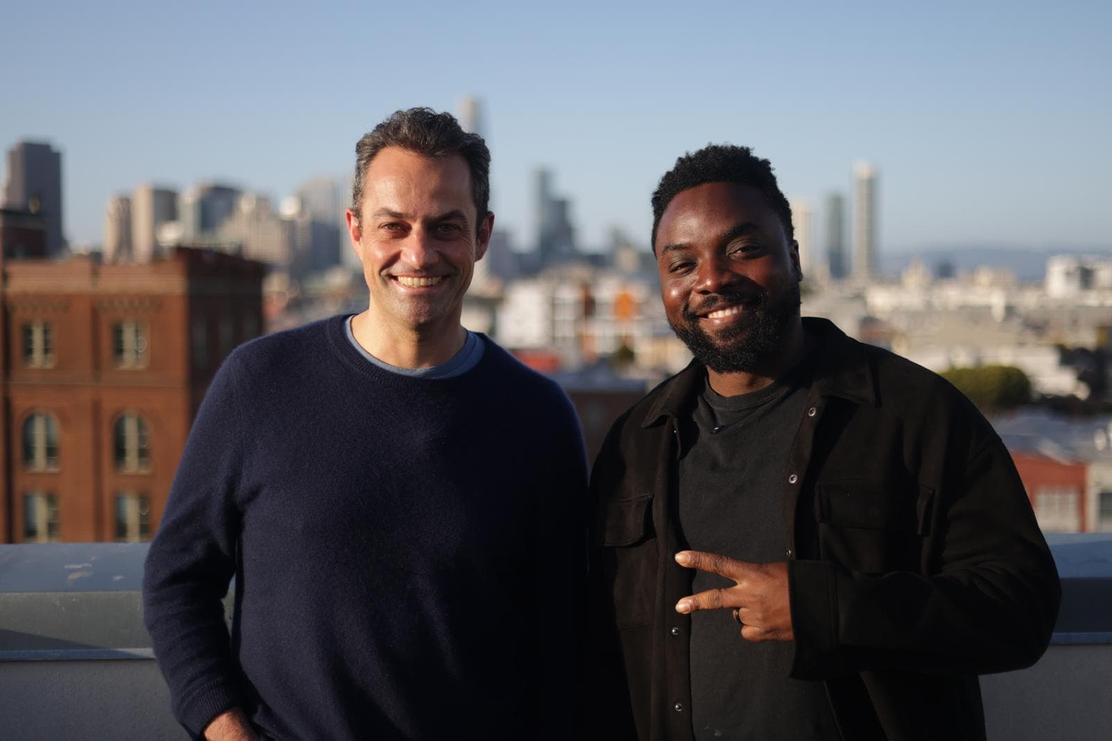Papa and a guest smiling on a San Francisco rooftop at golden hour.
